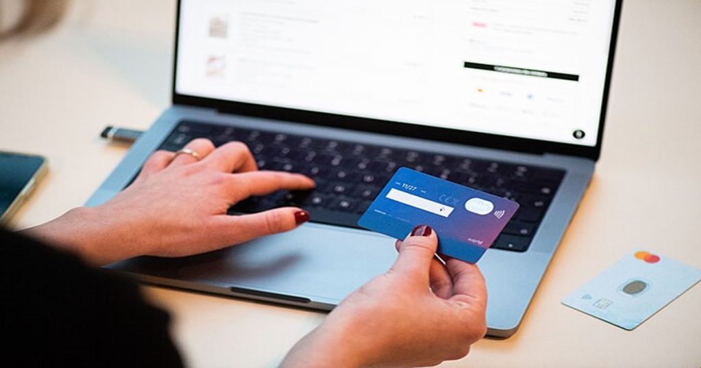 věci na internetu, žena s platební kartou u klávesnice PC